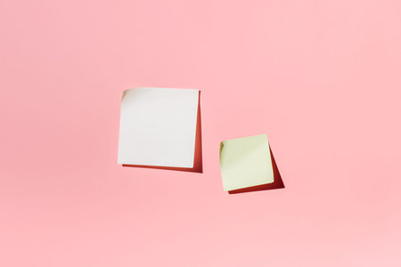 Blank sticky note pad and green sticky note on pink background
