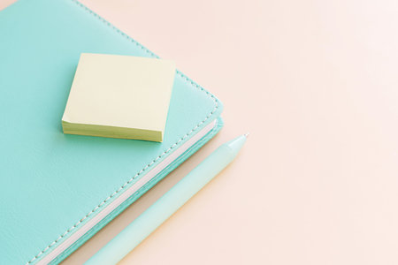 Notebook with sticky notes and pen on soft pastel workspace