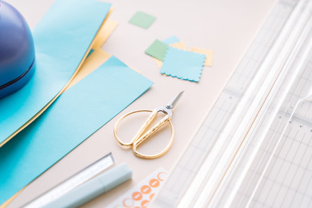 Craft workspace with paper cutter, scissors and colorful paper pieces on pastel background, DIY scrapbooking flat layの写真素材