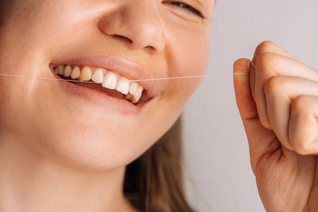 Smiling woman pulling dental floss, close up dental hygiene and prevention concept