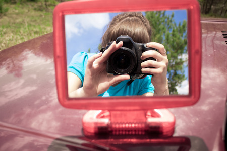 Pictures in the mirror on the hood of the car in the field 