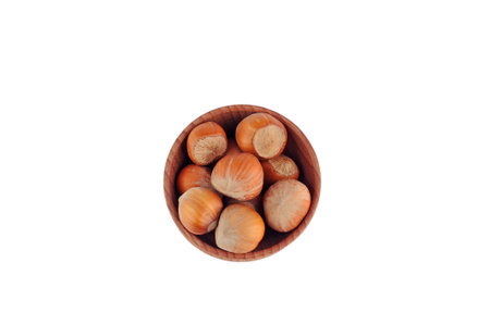 Hazelnuts in a wooden bowl on the white background