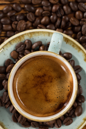 Smell the aroma. Cropped top view shot of a cup of coffee surrounded by coffee beans.の写真素材