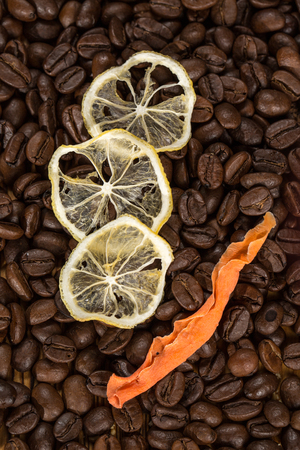 Aromatic mix. Shot of two dried lemon slices and a dried pumpkin slice lying on coffee beans scattered on the table.の写真素材