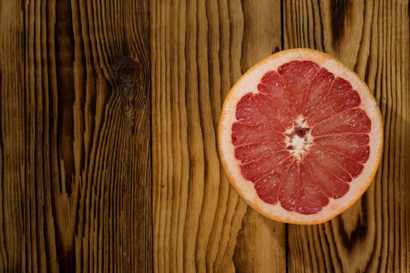 Smell of summer. Top view of a half of a grapefruit on a wooden surface copyspace on the side.の写真素材