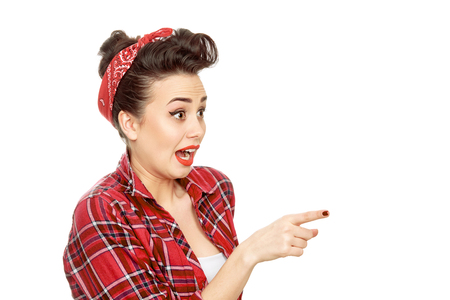 Whaaaat? Portrait of a beautiful pinup girl in a plaid shirt wearing a red bandana in her hair looking surprised shouting and pointing at the copyspace isolatedの写真素材