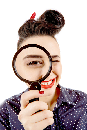 Hottest detective. Closeup portrait of a funny red lipped pinup girl looking to the camera through a magnifying glassの写真素材
