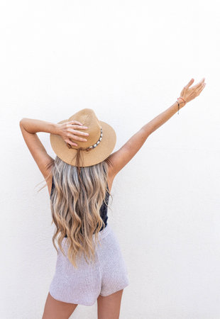 Rear view of young woman with long blonde hair wear a hatの写真素材