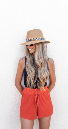 Smiling young woman with a long blonde hair and hatの写真素材