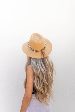 Rear view of young woman with long blonde hair wear a hatの写真素材
