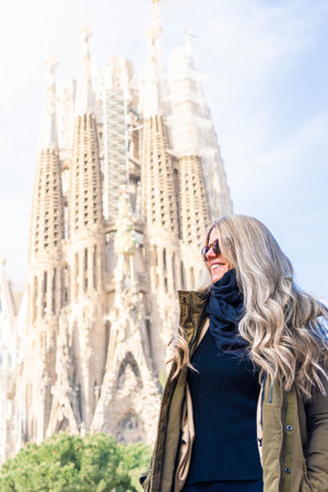 Tourist woman with blonde hair visiting The Sagrada Familia of Barcelonaの写真素材