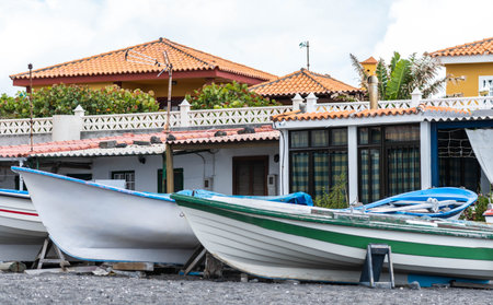Boats on the black beach in the coast of the village. Houses near the embarcartionsの写真素材