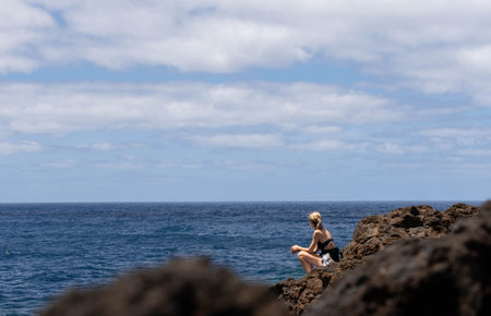 Seascape with woman in backwards with blonde hair in the distance looking the seaの写真素材