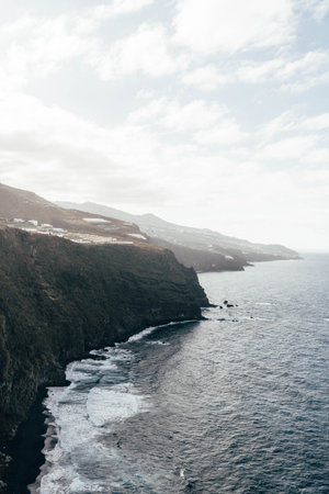 Savage seascape with impressive cliff and rocks. Heavy waves in the beach with black sand.の写真素材