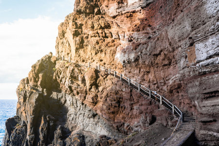 Woman standing on the stairs in heavy and savage craggy mountain near the seaの写真素材