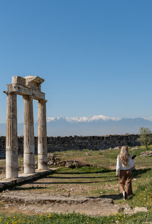 Rear view of woman at Roman ruins with snow-capped mountain peaks in the backgroundの写真素材