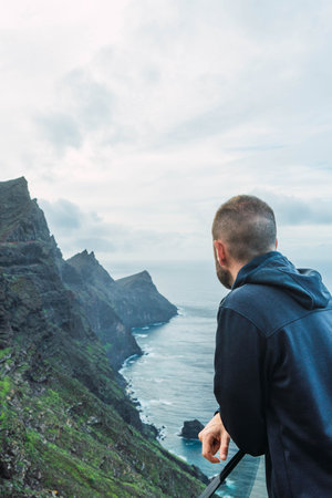 Man at a viewpoint watching the seascape in a cloudy day