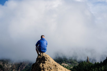 Man sitting on a rock with the amazing view of Roque Nublo in Gran Canariaの写真素材