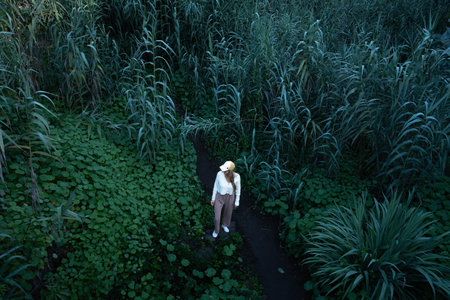 Blonde woman surrounded plants in the middle of the green natureの写真素材