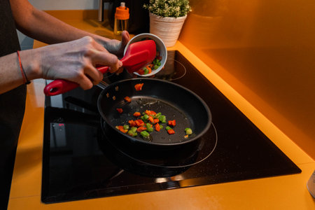 Unrecognizable person throwing vegetables in a frying pan