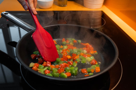 Unrecognizable hand cooking vegetables in a frying panの写真素材