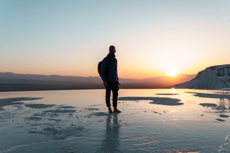 Traveller man with backpack in Pamukkale in the middle of sunset in travertinesの写真素材