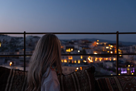 Blonde woman looking Cappadocia town with lights of the street in the nightの写真素材
