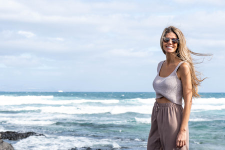 Portrait of woman with blonde hair looking at the camera near the seaの写真素材