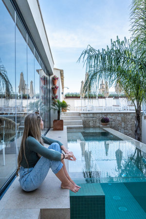Caucasian woman with long blonde hair resting near the pool looking the cloudsの写真素材