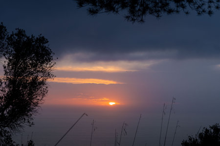 Sunset view in calm sea surface. Idyllic orange sundown above the cloudsの写真素材
