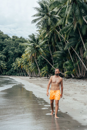 Handsome fit and healthy man walking on the Beach looking out to seaの写真素材