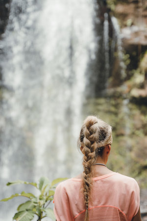 Rear view of blonde woman hiker watching waterfall inside rain forest in Panamaの写真素材