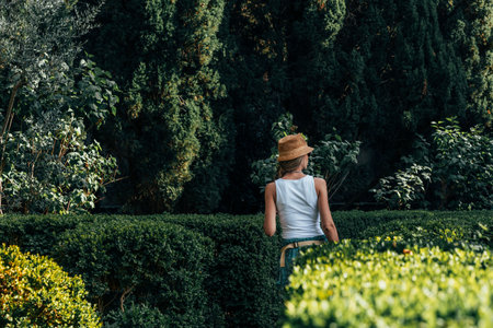 Rear view of blonde woman with hat walking in the middle of the parkの写真素材