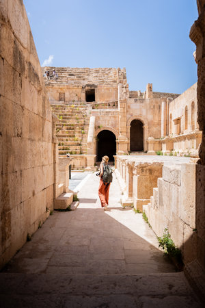 Rear view of tourist blonde woman with hat in Ancient Jerash ruins, Jordanの写真素材