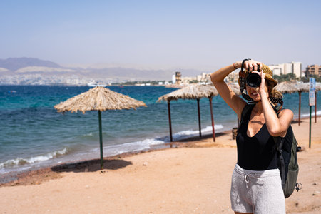 Blonde tourist woman doing a photography walking in the beach of Aqaba, Jordanの写真素材