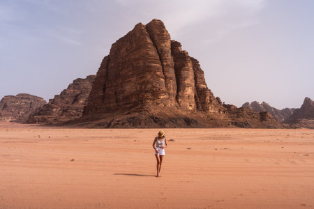 Blonde tourist woman walking of Sand Dune and Amazing Rock in Wadi Rum desert, Jordanの写真素材