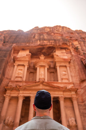 Rear view of man in spectacular view of Al Khazneh (The Treasury), ancient city of Petra, Jordanの写真素材