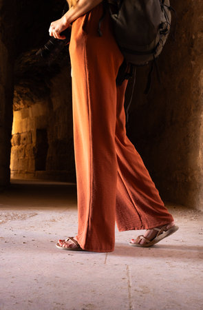 Unrecognizable woman with backpack walking on old floor background, concept of travel and goals.