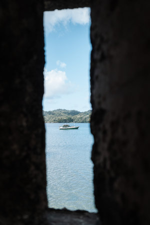 Small boat can be seen through an opening of a stone wall