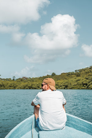 Man with cap and sunglasses sitting on the edge of a boat floatingの写真素材