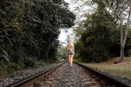 Woman walking along a solitaire rail track in the jungleの写真素材