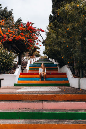 Woman relaxing on colorful steps surrounded by vibrant flowersの写真素材