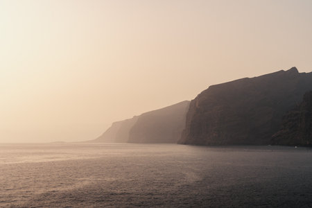 Serene coastline Los Gigantes at dusk capturing the tranquil waves and cliffsの写真素材