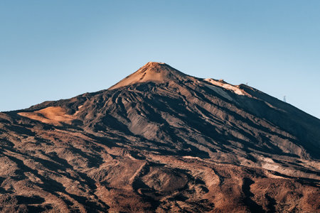 Teide mountain with a dark brown peak and a blue sky in the backgroundの写真素材