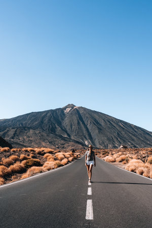 A woman is walking down a road in front of a Teide, Tenerifeの写真素材