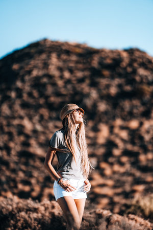 Young woman enjoying a sunny day outdoors against a rocky mountain backgroundの写真素材