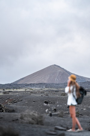 Defocused woman exploring a volcanic landscape with a distant mountainの写真素材
