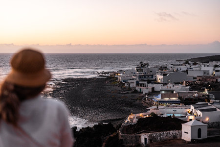 Defocused woman gazes at sunset over coastal town in El Golfo in Lanzaroteの写真素材