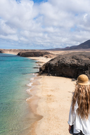 Papagallo beach view with woman standing on the shore during in Lanzaroteの写真素材