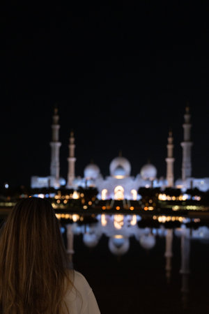 Rear view of tourist admiring sheikh zayed grand mosque at night in abu dhabi